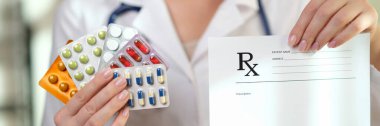 Kadın doktorun elinde boş reçete kağıdı ve renkli haplardan oluşan kabarcıklar var. Eczane ve doğru doz uyuşturucu konsepti