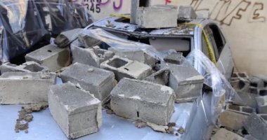 Otoparktaki kırık arabanın ön camında beton bloklar var. Araba sigortası ve deprem
