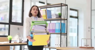 Ofiste bir yığın dosya taşıyan yorgun bir iş kadını. Fazla çalışma ve kağıt bürokrasisi