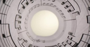 Üzerinde müzik notaları olan beyaz bir kağıt. Yakından sarmalanmış ve parlak bir ışık. Müzik eğitimi