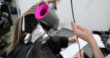 Saç boyası, folyodaki yeniden uzamış saç kökleri, sarışın, kuaför renkçisi ve güzellik salonu. Kuaför salonu müşterisi tedavi ve saç boyası alıyor