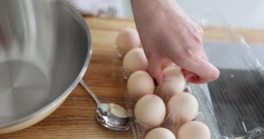Kadın mutfaktaki kasede pişirmek için yumurta ve un alıyor. Yumurta tabakları.
