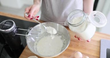 Kadın, mutfakta kek veya hamur hazırlarken kaseye un döker. Kasede hamur hazırlanıyor.