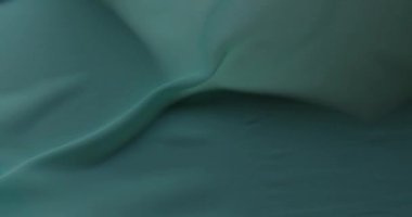 Yeşil pamuk kumaş dalgaları yaklaşıyor. Bataklık yeşil kumaşının koyu arkaplanı