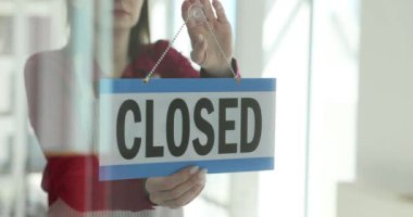 Kadın, iş gününün başında açık kapı tabelasını ters çeviriyor. Küçük iş kurma