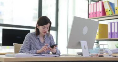 Ofiste akıllı telefondan konuşan bir kadın zaferi kutluyor. Neşeli satış müdürü müşteri ve başarı duygularıyla cep telefonuyla konuşuyor