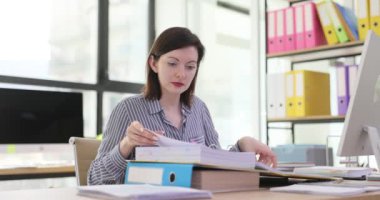 Ofiste masa başında çalışan kadın belgeleri düzenliyor. İş belgeleriyle çalışmak