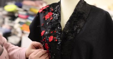 Kırmızı çiçekli siyah elbise ve atölyedeki mankenler üzerine dikilmiş elbise. Tasarımcı ve moda terziliği