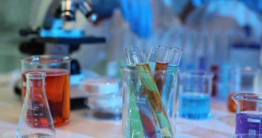 Renkli kimyasal reaksiyonlarla yapılan laboratuvar deneylerinin incelenmesi. Renkli sıvılarla dolu çeşitli test tüpleri incelenir ve bilimsel araştırmalar kanıtlanır.