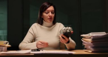 Ofiste gece alarmlı saat gösteren yorgun bir yönetici kadın. Çok çalışan bir ofis çalışanı gece geç saatlere kadar çalışıyor.