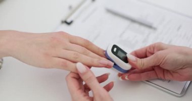 Doktor, nabız oksimetresi kullanarak ve klinikteki tıbbi kayıtları inceleyerek hastanın kanındaki oksijen seviyesini ölçer. Doktor hastanın oksijen durumunu değerlendiriyor.