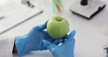 Kimyasal maddelerin laboratuardaki yeşil elmalar üzerindeki etkilerini inceliyorum. Bilim adamı laboratuvarda yeşil bir elma inceliyor.