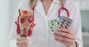 Sindirim sisteminde insan anatomisi ve klinikte ilaç kullanımı. Doktor proktolog hapları ve insan rektumunun yapay modelini tutuyor.