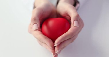 Şefkatli eller sevgiyi, ilgiyi ve barışı simgeleyen kırmızı bir kalp tutar. Etkili tedavi için sağlık hizmeti sağlayıcısı