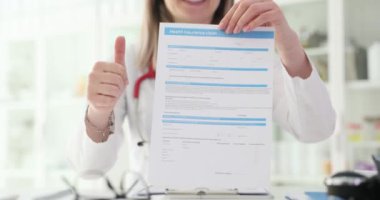 Klinikte sağlık sigortası konusunda başarılı bir danışmanlık. Doktor sağlık sigortası için başvuru izni ve elinde baş parmak tutan doktor.