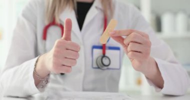 Doktor bandaj, alçı ve baş parmağını kaldırdığını gösteriyor. Bandaj tamiri ve alçı önerisi için en iyi alçı.