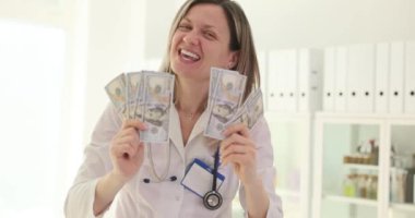 Doktor para gelirini gülümseyerek ve sevinerek gösteriyor. Pahalı tedavi, tıptaki yolsuzluk