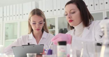 İki bilimadamı laboratuvarda menekşe reaktörü üzerinde detaylı bir çalışma yürütüyor. Laboratuvar yeni formül ve asit testi şeridi üzerinde çalışıyor.