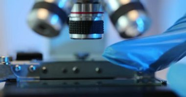 Bilimsel deneyler için mikroskop hazırlıyorum. Cam mikroskoba yerleştiriliyor.