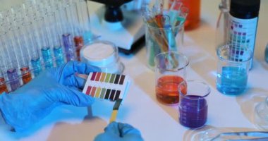 Laboratuvarda litmus kağıdı kullanarak sıvının pH seviyesini kontrol ediyorum. Bilim adamı kimyager ph testi yapıyor.