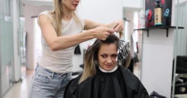 Renkçi kuafördeki müşteri saçlarına röfle uyguluyor. Renkli saçlı profesyonel bir kadın.