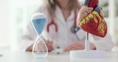Doktor klinikte kalp anatomik modelini kum saatiyle inceliyor. Kalp cerrahisi hastalarının rehabilitasyonu