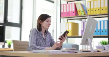 Yorgun bir kadın gün içinde ofis masasında akıllı telefon kullanır. İş yerindeki sinirli çalışan yönetici kadın.