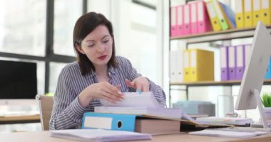 Gündüz vakti modern ofiste dosyaları düzenleyen bir kadın. İş kadını sekreteri iş belgeleriyle çalışıyor