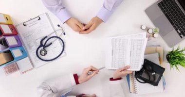 Doktor ve hasta kardiyogram sonuçlarını inceliyor. Norm ve patoloji belirtilerinin EKG açıklaması