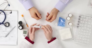 Doktor muayenehanedeki hastaya kan şekeri testi uygular. Kan şekeri izleme
