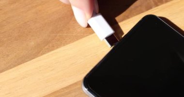 USB-C kablosu masadaki akıllı telefona bağlanıyor. USB bağlantısını şarj güç bankasına bağla