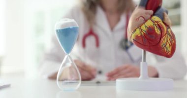 Kalp ve kum saatinin doktor modeli kardiyolog muayenehanesinde. Kalp ritmi bozukluklarının tedavisi