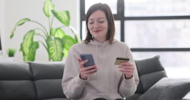 Kadın internet üzerinden kredi kartı ve akıllı telefon kullanarak alışveriş yapıyor. Alışveriş ve ödeme çevrimiçi