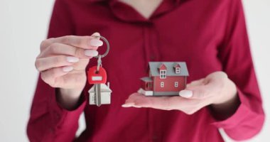 Emlakçı evin anahtarlarını ve modelini tutuyor. Kiralık ev.