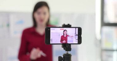 Ofisteki akıllı telefondan videoyu kaydeden bir kadın. Blogger analisti grafiklerde analitik öneriyor