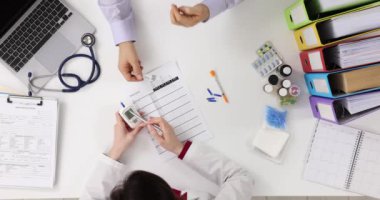 Doktor ve hasta klinikte kan şekeri testi yaptırıyor. Diyabetin teşhisi ve tedavisi