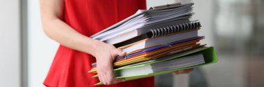 Sekreter içinde muhasebe malzemeleri olan klasörleri iş yerine götürüyor. Evrak işleri için hazırlanan dosyaları ve kitapları elinde tutan kadın.