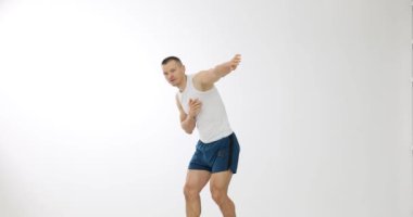 Adam beyaz arka planda dans egzersizleri yapıyor. Genç adam elleriyle dans ediyor.