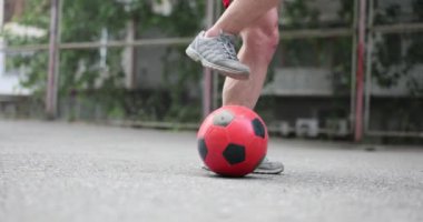 Sahada kırmızı futbol topunu tekmeleyen erkek bacakları. Futbol antrenmanı.