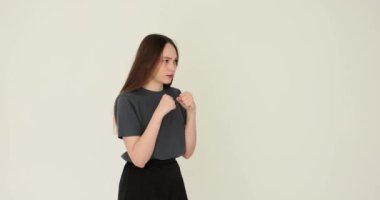 Kadın, beyaz arka plana karşı nefsi müdafaa için temel vuruş tekniğini gösteriyor. Yumruk pratiği yapan kız