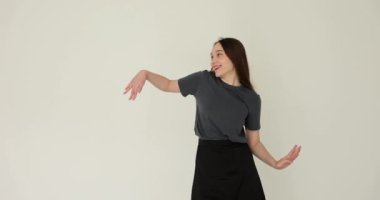 Dans eden genç bir kadın beyaz arka planda el hareketi yapar. Öğrenci kız elleriyle yumuşak hareketler yapıyor.