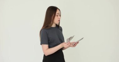 Beyaz arka planda dolar sayan gülümseyen genç bir kadın. Kız öğrenci ve ilk maaş ve mali yatırımlar