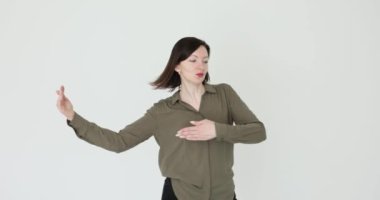 Kadın elleriyle hareket eder ve yalnız dans eder, stüdyodaki çift gibi. Beyaz arka planda dans eden heyecanlı kadın portresi