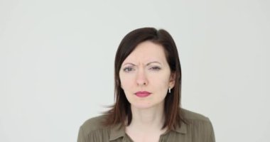 Beyaz arka planda şüpheli görünen ve şüpheli görünen bir kadın. Gözleri bozuk bir kadın kameraya bakıyor.