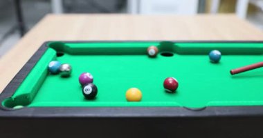 Oyuncu küçük bilardo topları ve masada ıstaka ile oynuyor. Ev için bilardo masası oyunu
