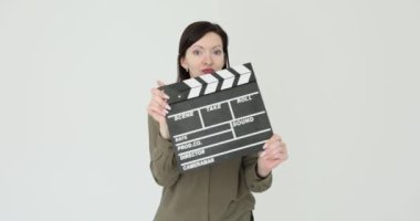 Kadın beyaz arka planda çekim yapmak için el çırpma tahtası tutuyor. Kadın yönetmen yardımcısı film çekerken alkışları çakıyor