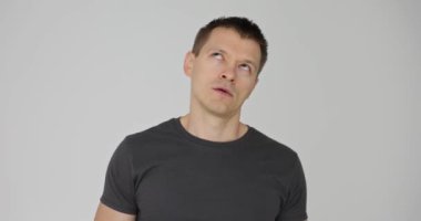 Beyaz arka planda kafası karışmış bir ifadeyle yukarı bakan bir adam. Sinirli genç adam gözlerini yuvarlıyor.