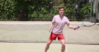 Adam güneşli bir günde tenis kortunda hizmet etmeye hazırlanıyor. Tenis oyunu