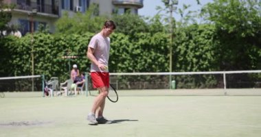 Adam tenis kortunda raket ve topla yürüyor. Tenis maçı için hazırlık ve ısınma