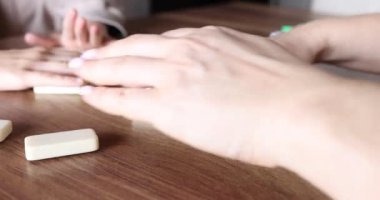 Tahta bir masada arkadaşlarla domino oynamak. Yetişkin ve çocuk domino bloklarını karıştırıyor